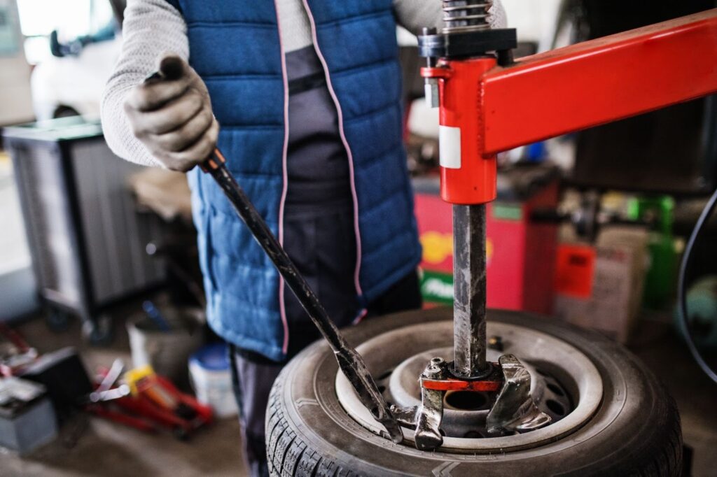 Auto mechanic removing a tire from the wheel using a tire changing machine